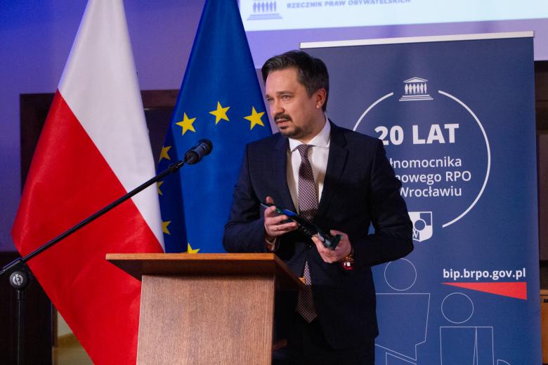 Marcin Wiącek wypowiada się do mikrofonu trzymając statuetkę nagrody