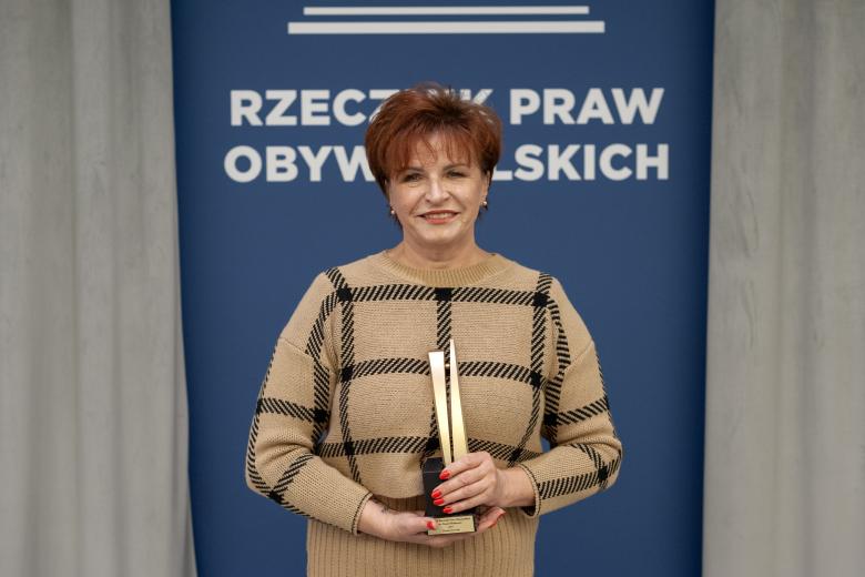 Urszula Jaworska pozuje do zdjęcia trzymając statuetkę nagrody i uśmiechając się