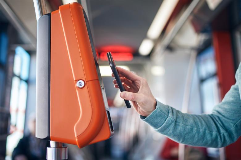Osoba przykłada telefon do terminala biletowego w autobusie komunikacji miejskiej