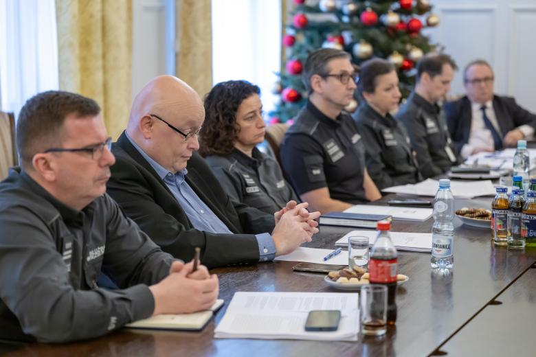 Kilka osób w mundurach siedzi przy dużym stole konferencyjnym