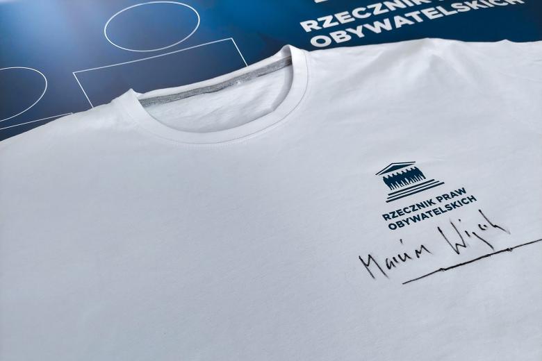 Zbliżenie na nadrukowane logo RPO i podpis Marcina Wiącka na koszulce