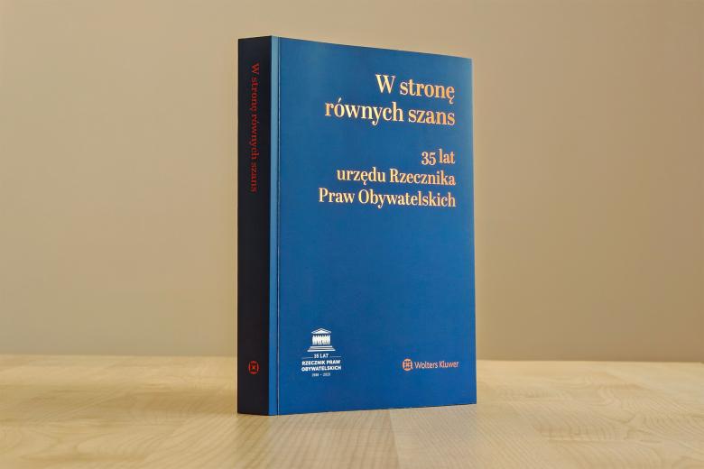 Książka stojąca na blacie biurka. Na okładce napisane jest "W stronę równych szans - 35 lat urzędu Rzecznika Praw Obywatelskich"