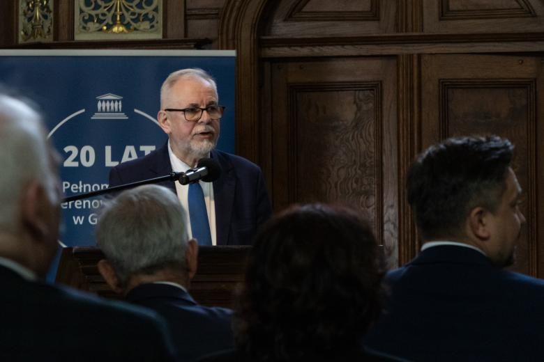 Osoba przemawia za mównicą, w tle granatowy rollup z napisem "20 lat Pełnomocnika Terenowego RPO w Gdańsku"