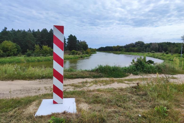 słup w biało-czerwone pasy w tle zakole rzeki 