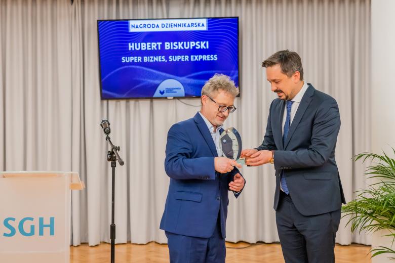 Marcin Wiącek wręcza Hubertowi Biskupskiemu statuetkę nagrody, uśmiechając się.