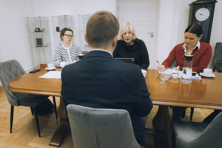 Cztery osoby siedzą przy stole i rozmawiają