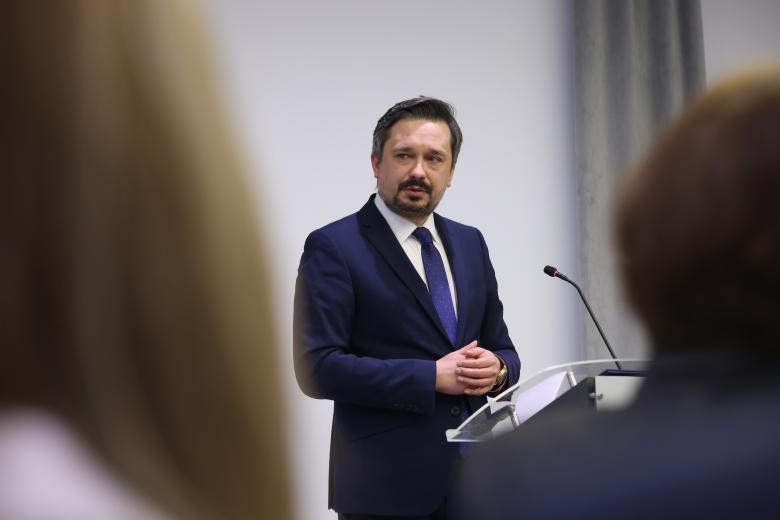 Marcin Wiącek wypowiada się stojąc przy mównicy.