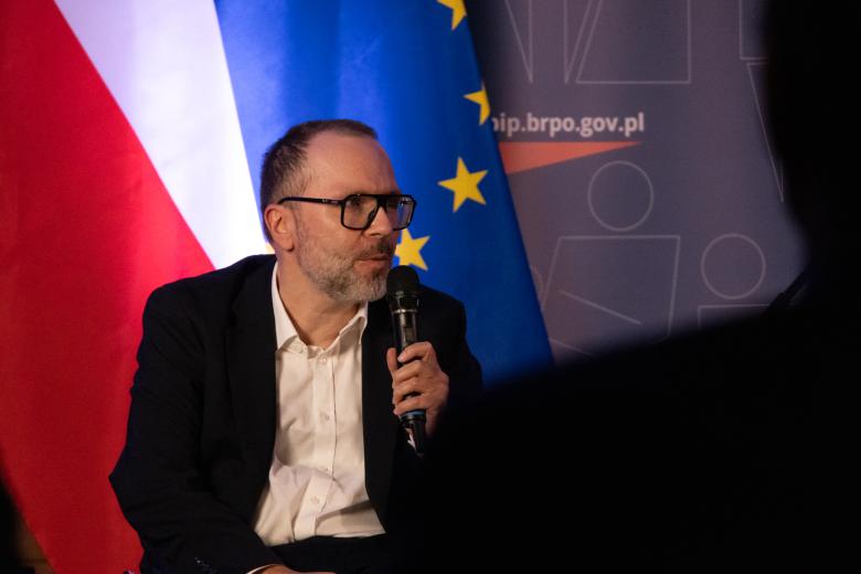 Tomasz Sługocki wypowiada się do mikrofonu.