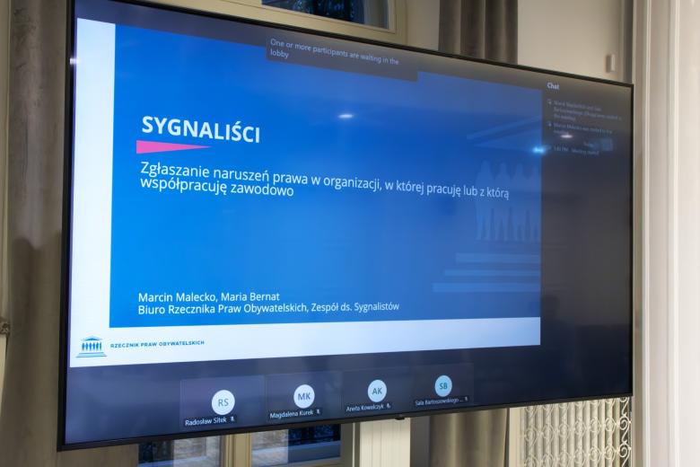 Ekran projektora z napisem "Sygnaliści. Zgłaszanie naruszeń prawa w organizacji, w której pracuję lub z którą współpracuję zawodowo"