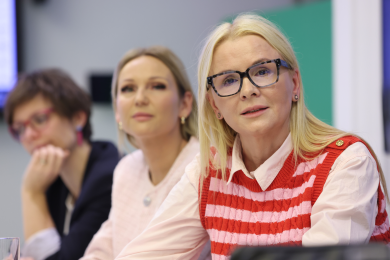 trzy kobiety siedzą w sali 