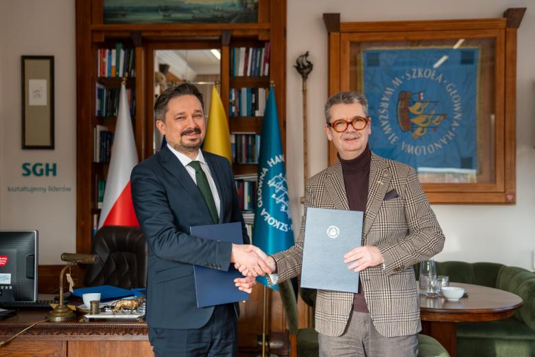 Dwie osoby pozują do wspólnego zdjęcia ściskając dłonie