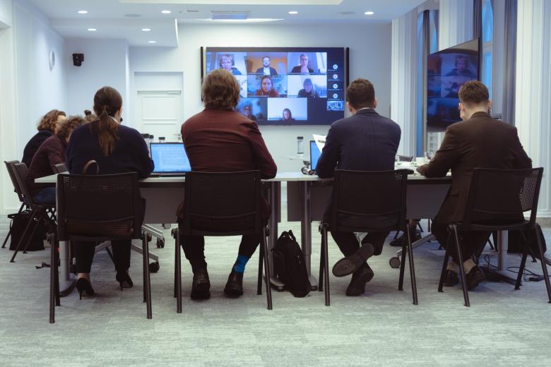 osoby siedzą w sali w tle ekran