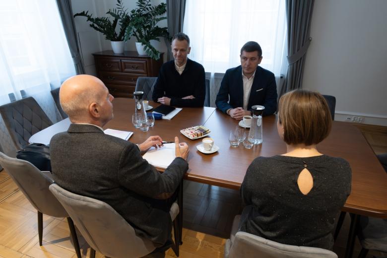 Cztery osoby siedzą przy stole i rozmawiają