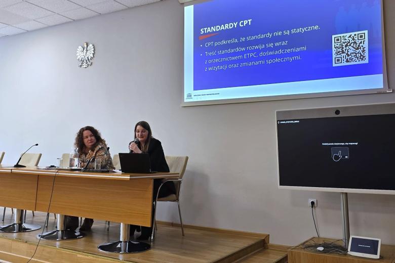 dwie osoby siedzą w sali 