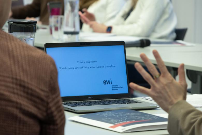 dłoń z otwartym laptopem w tle 