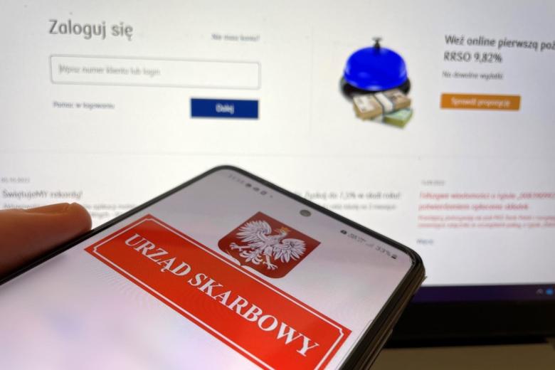 Smartfon z tekstem Urząd Skarbowy na ekranie, w tle na ekranie komputera ekran logowania do bankowości elektronicznej