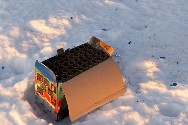 Zużyte opakowanie po zestawie fajerwerków leżące na śniegu