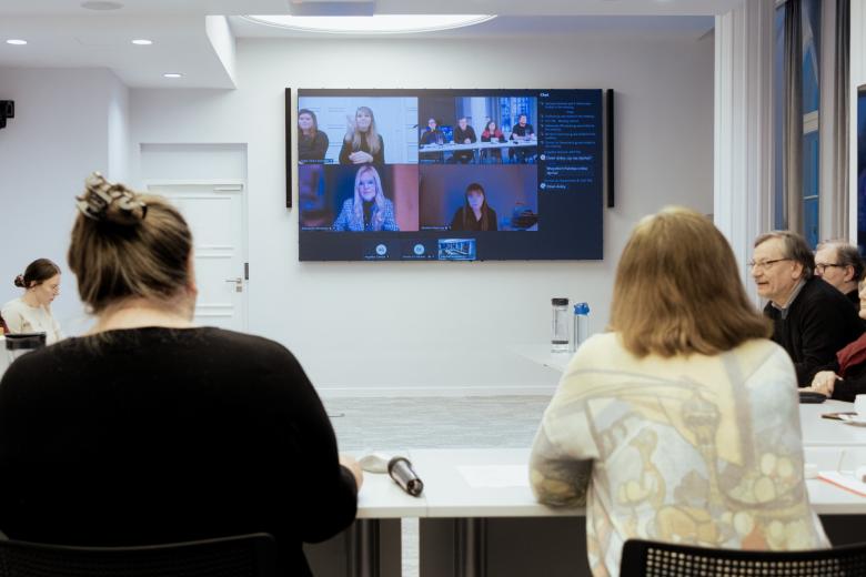 Duży ekran wyświetlacza z widoczną aplikacją do komunikowania się na odległość pomiędzy głowami uczestników spotkania stacjonarnie