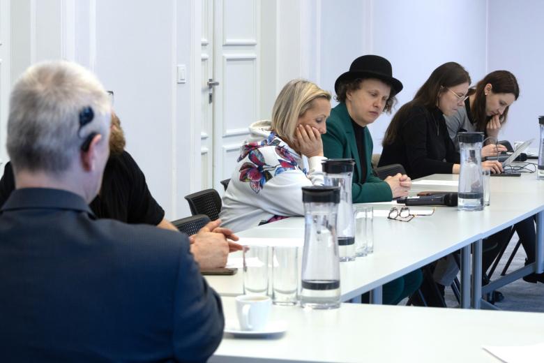 Kilka osób siedzi przy stole w sali konferencyjnej