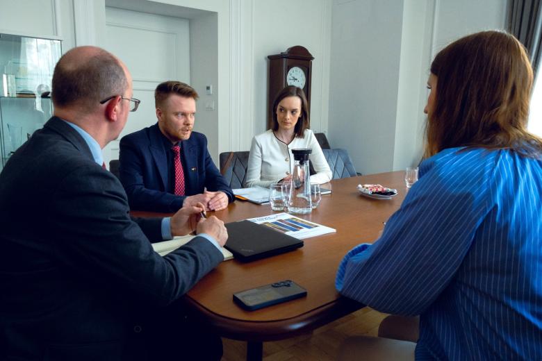 Cztery osoby siedzą przy stole i rozmawiają