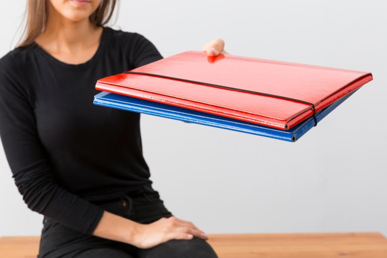 osoba trzyma kilka teczek dokumentów