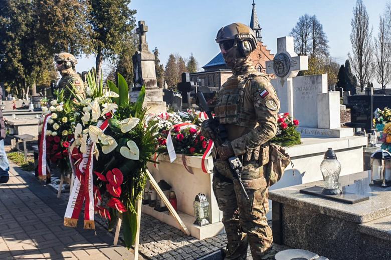 żołnierze z bronią stoją na warcie honorowej przy grobie