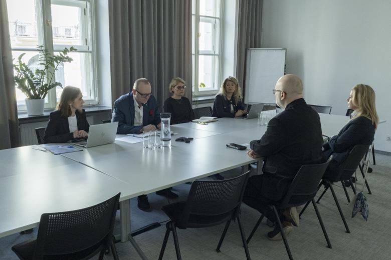 osoby siedzą w sali za stołem