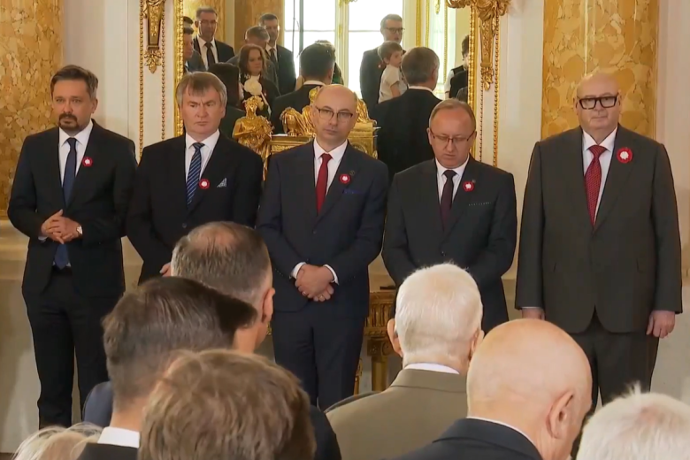 W bogato zdobionej sali pięć osób, w tym Marcin Wiącek, stoją w szeregu i uczestniczą w uroczystości