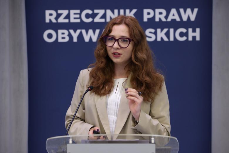 Osoba przemawia za mównicą, w tle napis "Rzecznik Praw Obywatelskich"