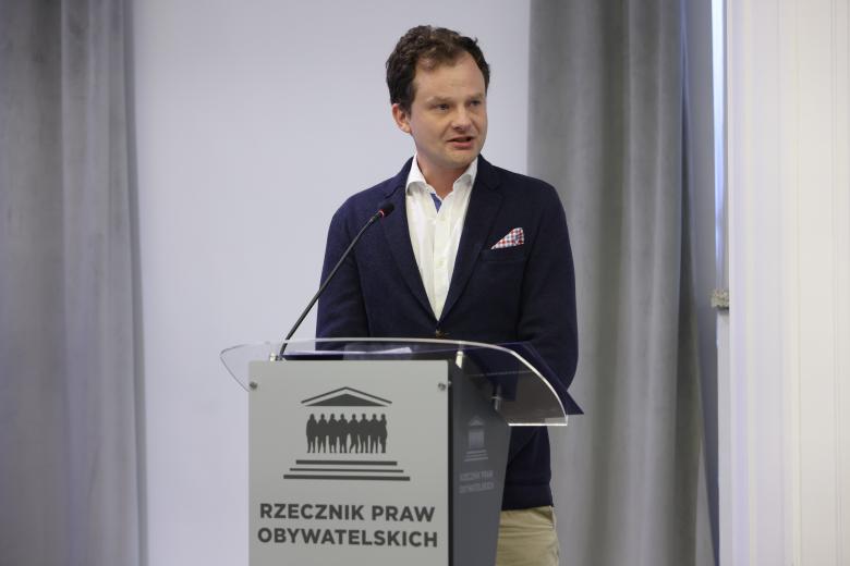 Adam Krzywoń wypowiada się stojąc przy mównicy