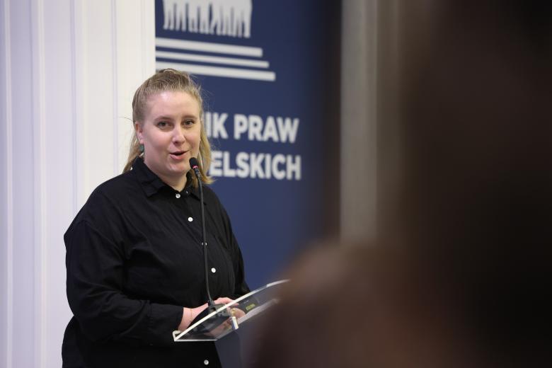 Katarzyna Kisil wypowiada się w stronę publiczności stojąc przy mównicy