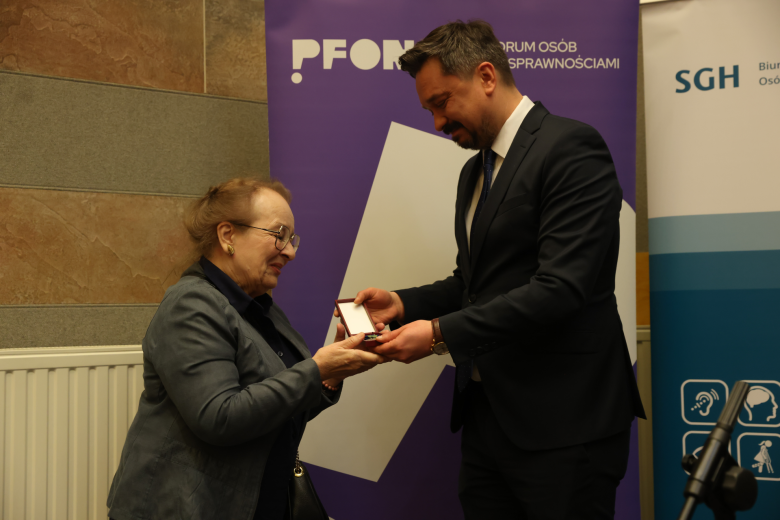 osoba wręcza innej  odznakę