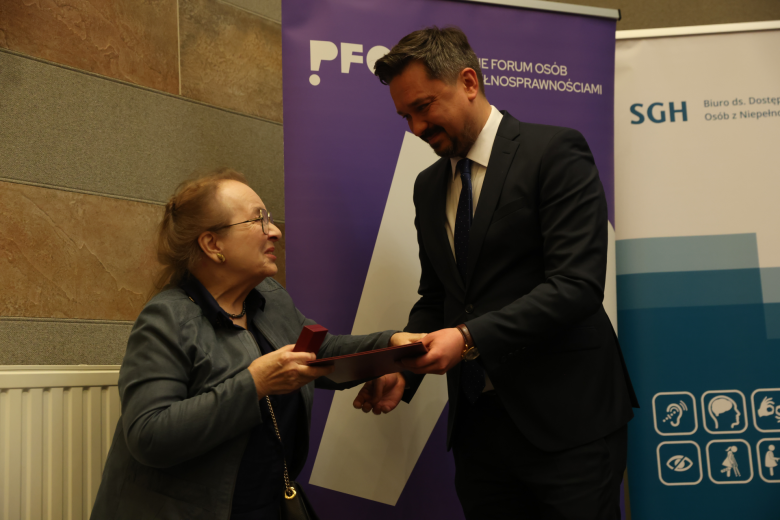 osoba wręcza innej  odznakę