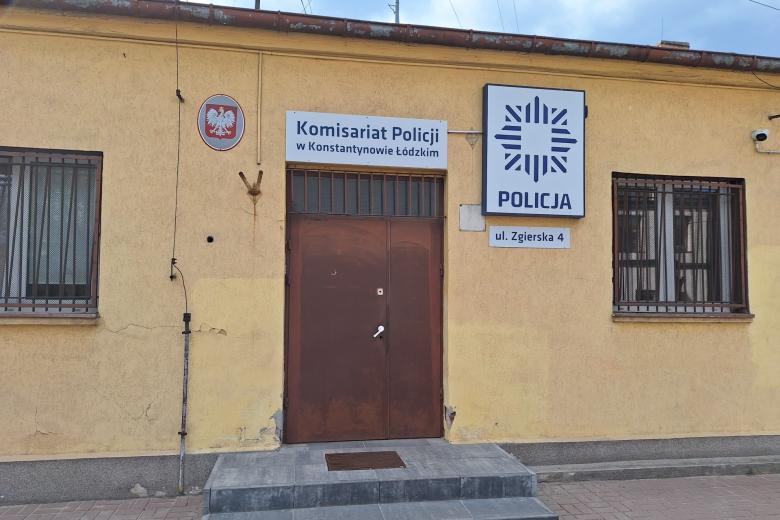 Stary, tynkowany, parterowy budynek z zardzewiałymi metalowymi drzwiami i kratami w oknach z napisem na ścianie "Policja"