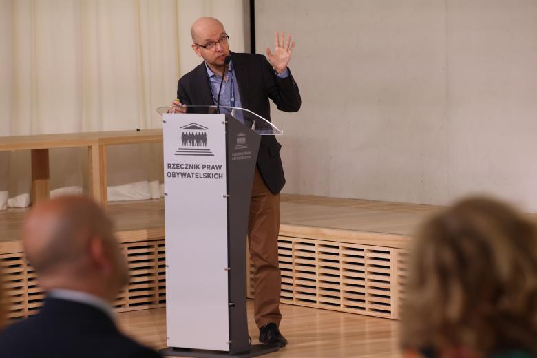  Gabor Petri wypowiada się stojąc przy mównicy i gestykulując