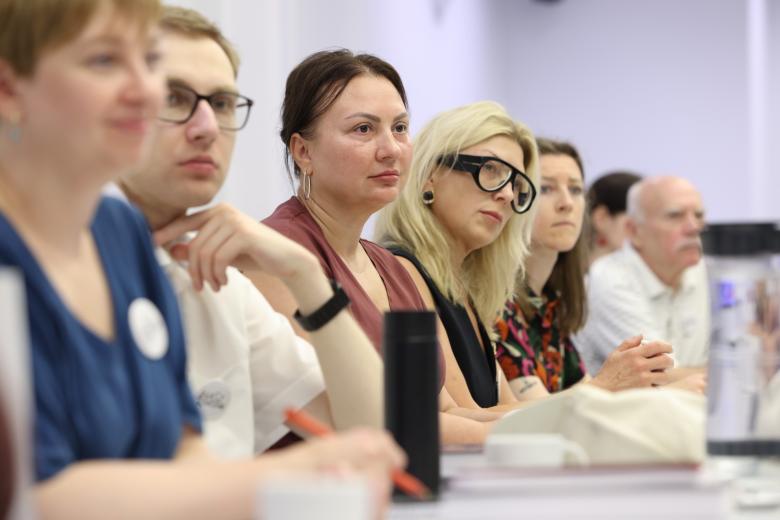 Rząd kilku osób siedzących przy stole w sali konferencyjnej