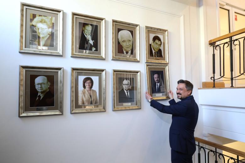 Osoba wiesza na ścianie z portretami nowy portret