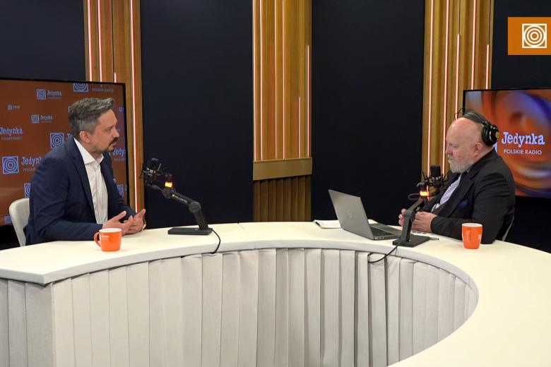 dwie osoby siedzą w studiu radiowym 