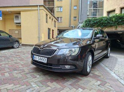 Samochód Skoda Superb II w ciemnym kolorze, widok z przodu i z lewej strony
