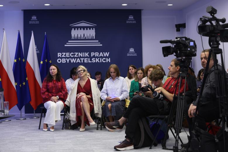 Kilkanaście osób siedzi na widowni w sali konferencyjnej