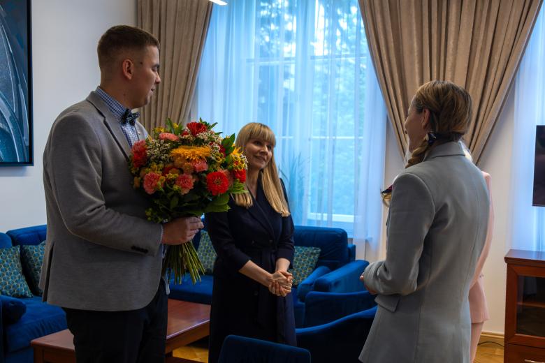 na zdjęciu widać trzy osoby - dwie - kobieta i mężczyzna - wręczają kwiaty RPO