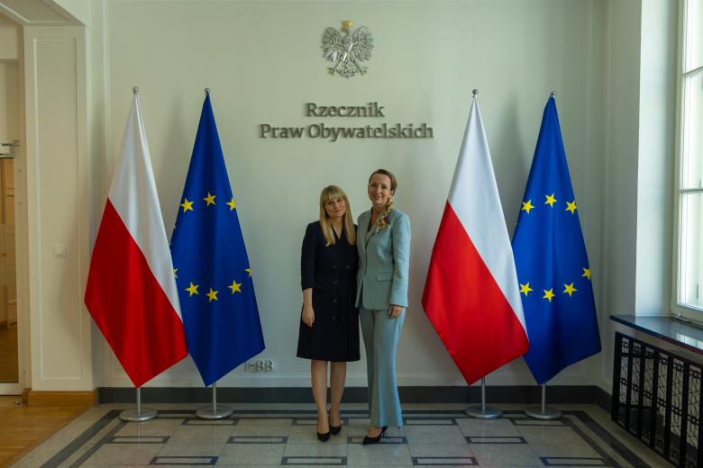 zdjęcie przedstawia dwie pozujące osoby - rpo i rpd - do zdjęcia na tle flag PL i UE