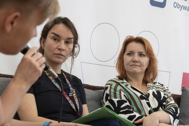 Dwie uczestniczki panelu i jeden z widzów rozmawiają. 