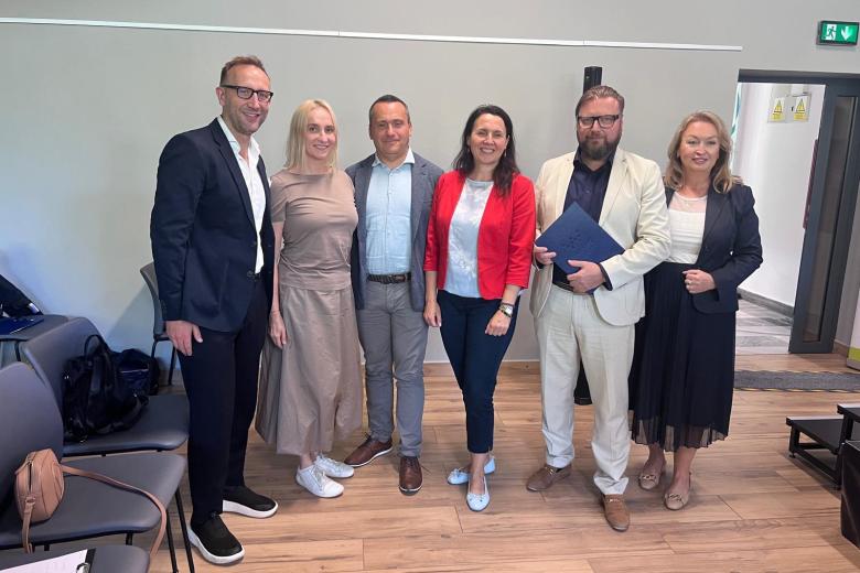 Sześć osób stoi i pozuje do wspólnego zdjęcia na sali konferencyjnej