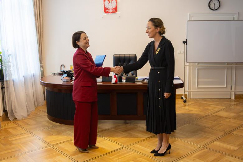 Sylwia Gregorczyk-Abram i Anna Błaszczak-Banasiak uśmiechają się i ściskają dłonie w gabinecie RPO