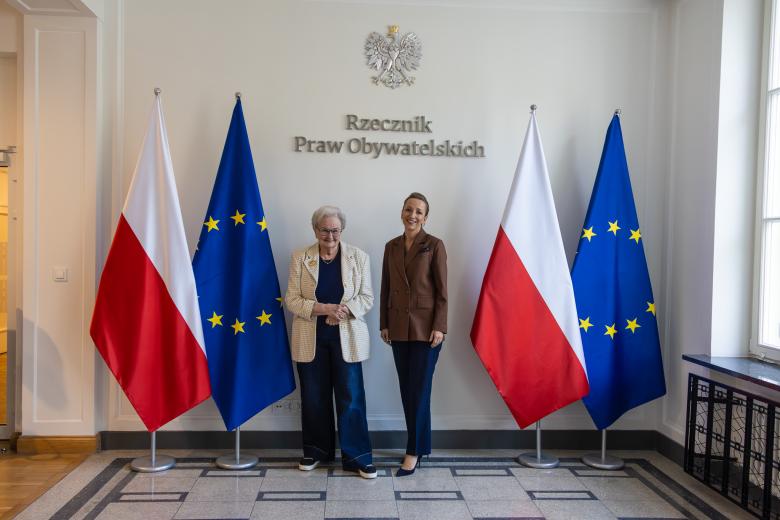 Ewa Łętowska i Sylwia Gregorczyk-Abram uśmiechają się, pozując do zdjęcia na tle napisu "Rzecznik Praw Obywatelskich" i flag Polski i Unii Europejskiej