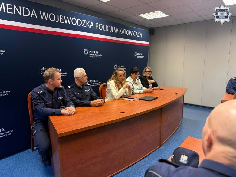 Pięć osób siedzi za stołem na tle napisu "Komenda Wojewódzka Policji w Katowicach"