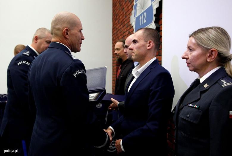 Grupa osób stoi i ściska sobie dłonie na powitanie