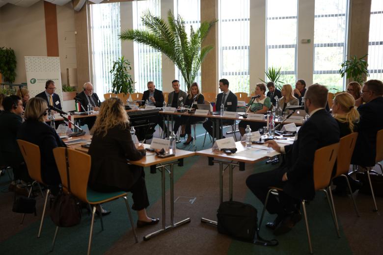 Duży stół ustawiony w kwadrat z ludźmi siedzącymi wokół na sali konferencyjnej