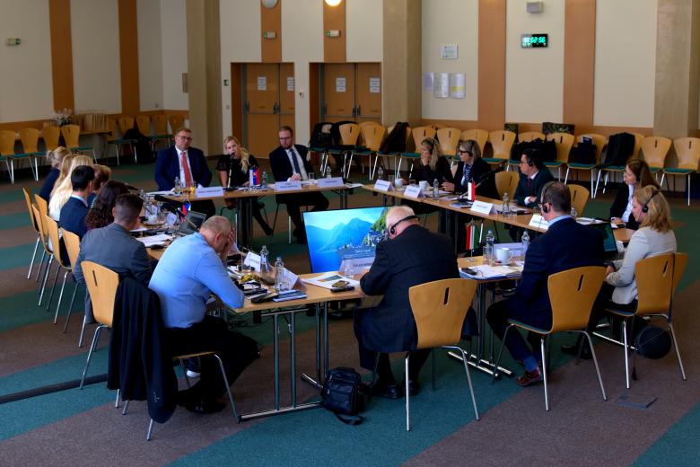 Duży stół ustawiony w kwadrat z ludźmi siedzącymi wokół na sali konferencyjnej